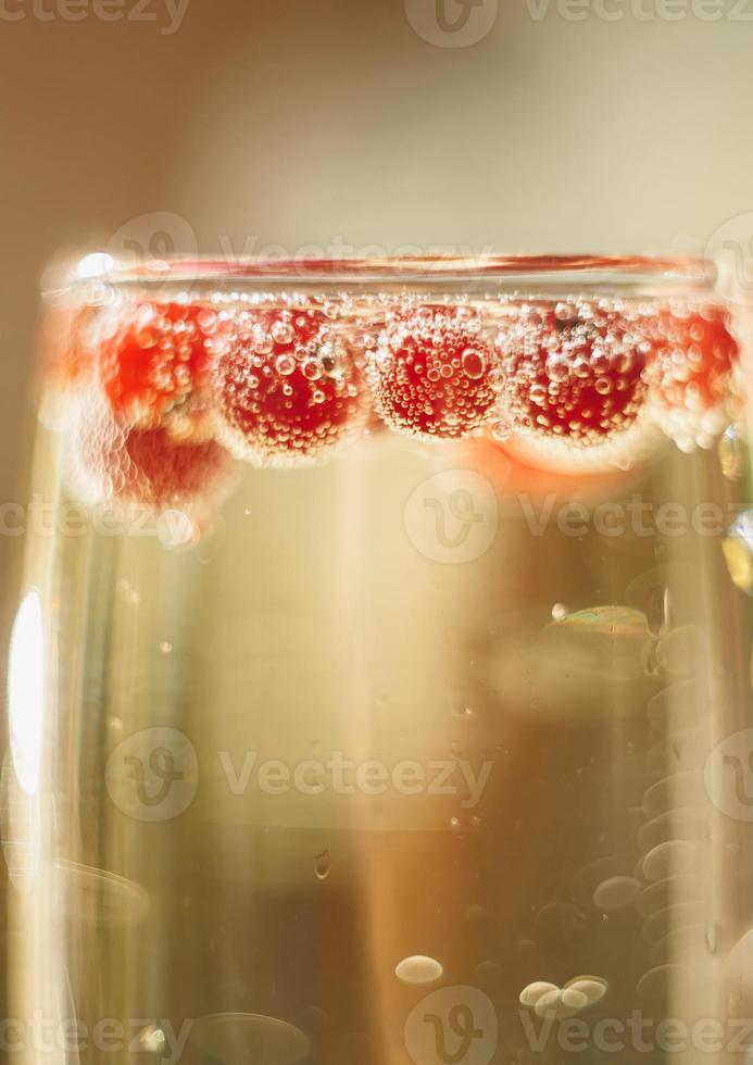 Sekt im Glas mit roten Johannisbeeren foto