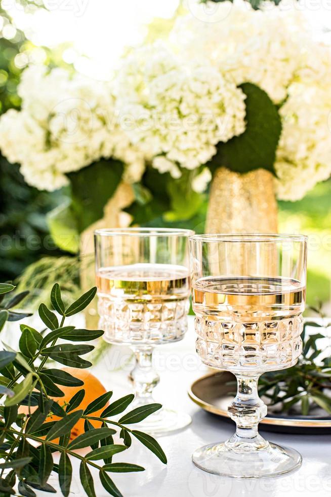 Roséwein in Gläsern auf goldenen Flaschen mit Blumen und Früchten foto