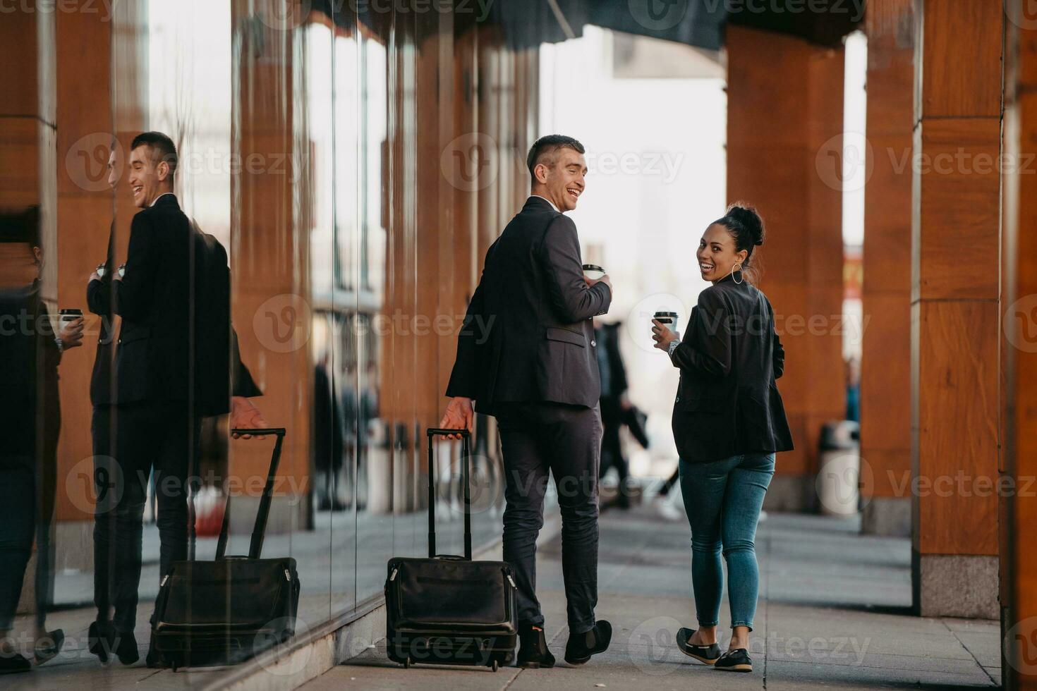 geschäftsmann und geschäftsfrau sprechen und halten gepäck auf einer geschäftsreise und tragen frischen kaffee in ihren händen. geschäftskonzept foto