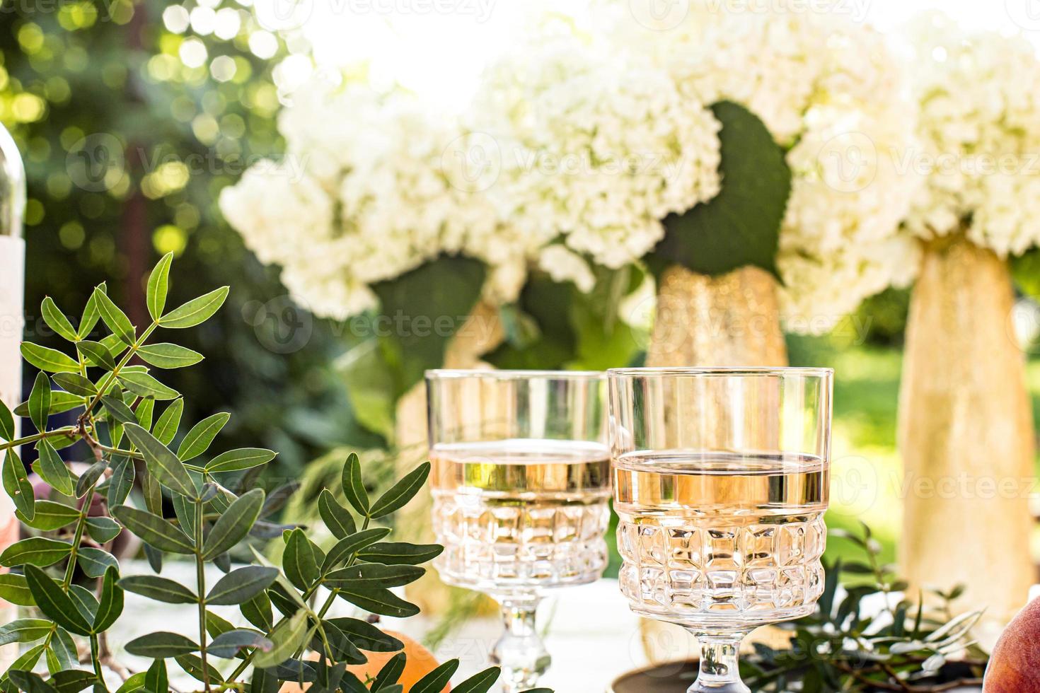 Roséwein in Gläsern auf goldenen Flaschen mit Blumen und Früchten foto