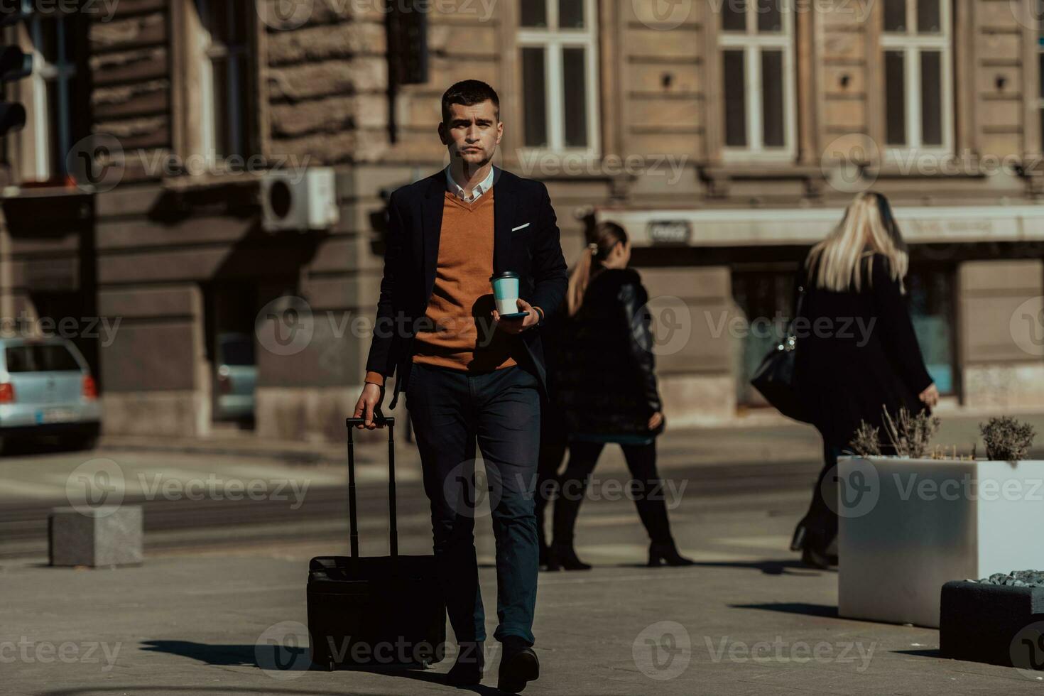 zum Flughafenterminal gehen. Selbstbewusster Geschäftsmann, der auf den Straßen der Stadt spazieren geht und seinen Koffer zieht, Kaffee trinkt und auf dem Smartphone spricht foto