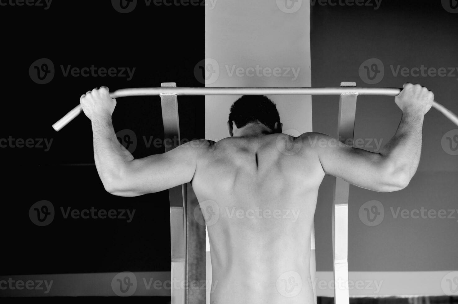 junger Mann mit starken Armen, der im Fitnessstudio trainiert foto