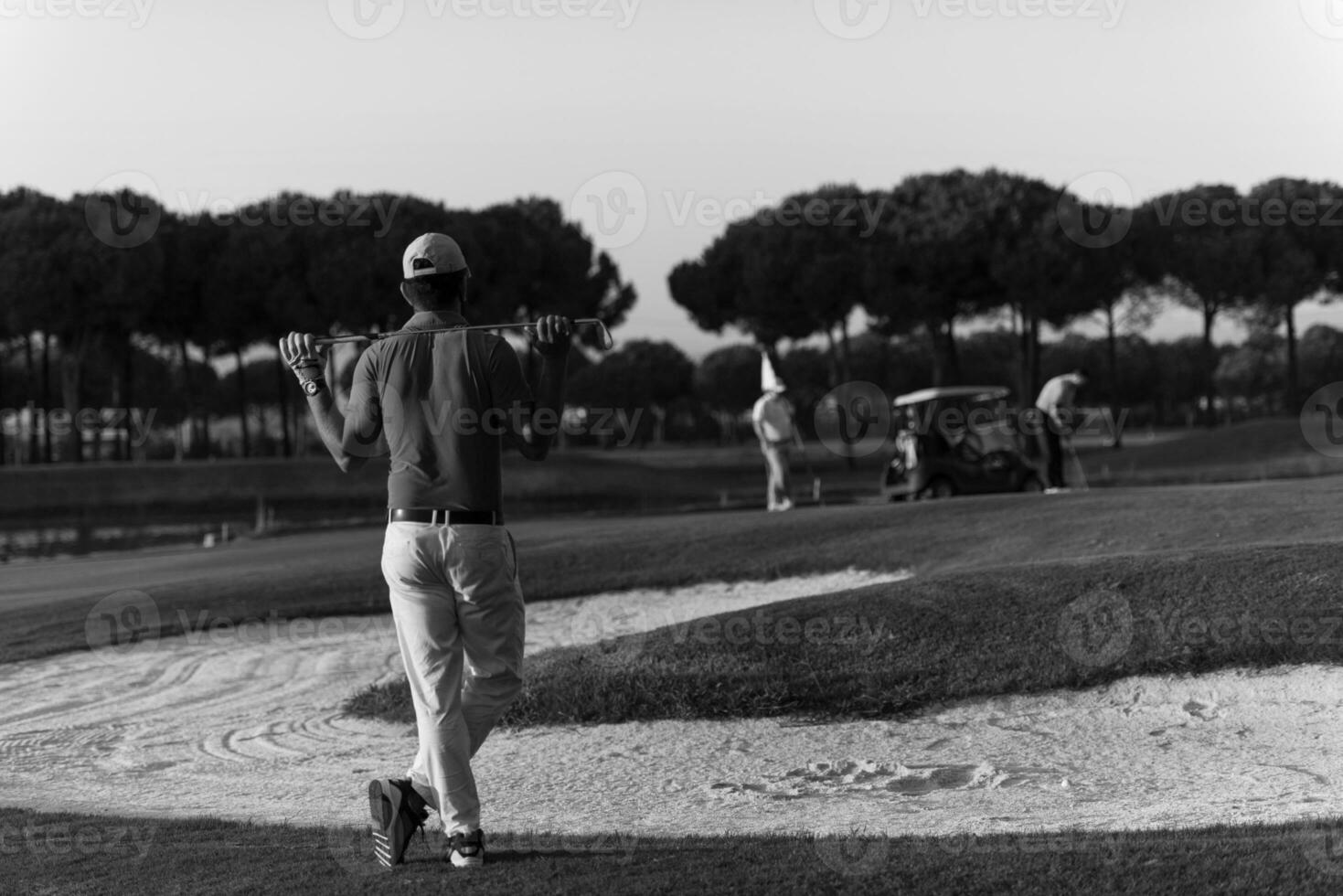 Golfer von hinten am Platz mit Blick auf das Loch in der Ferne foto