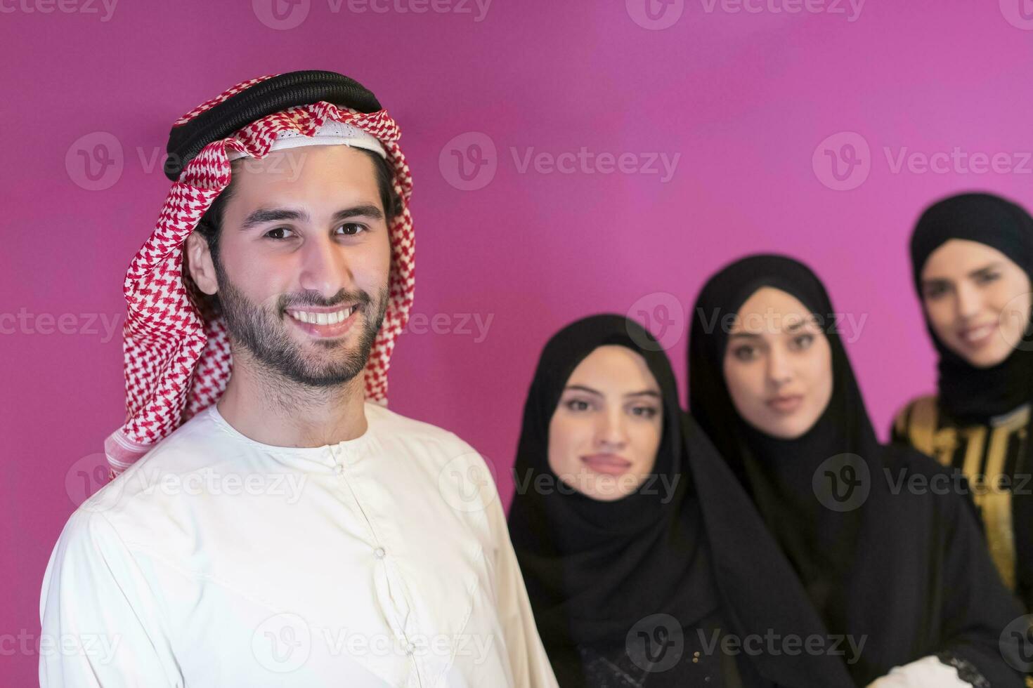 Gruppe Porträt von jung Muslim Menschen arabisch Männer mit drei Muslim Frauen im ein modisch Kleid mit Hijab isoliert auf ein Rosa Hintergrund foto