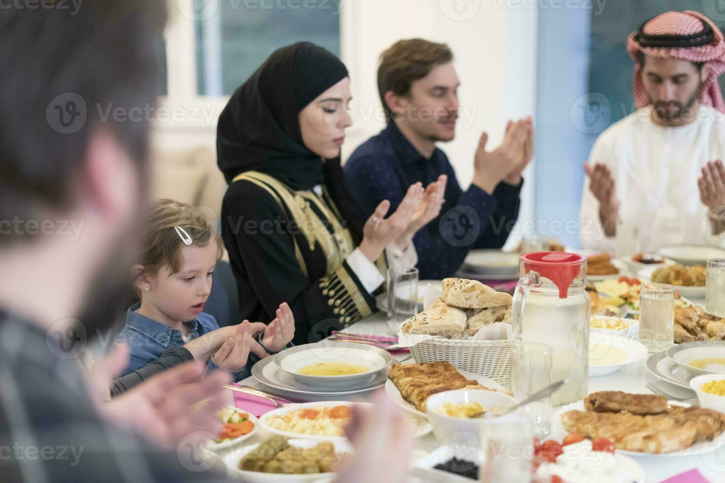 muslimische familie, die iftar dua macht, um während des ramadan das fasten zu brechen. foto