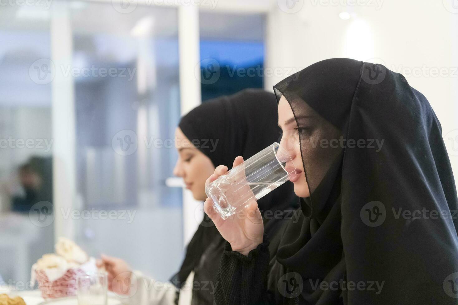 eid Mubarak Muslim Familie haben iftar Abendessen Trinken Wasser zu brechen Fest. Essen traditionell Essen während Ramadan schlemmen Monat beim heim. das islamisch halal Essen und Trinken beim modern Western isla foto