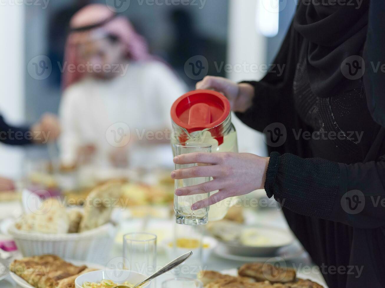 eid Mubarak Muslim Familie haben iftar Abendessen Trinken Wasser zu brechen Fest. Essen traditionell Essen während Ramadan schlemmen Monat beim heim. das islamisch halal Essen und Trinken beim modern Western isla foto