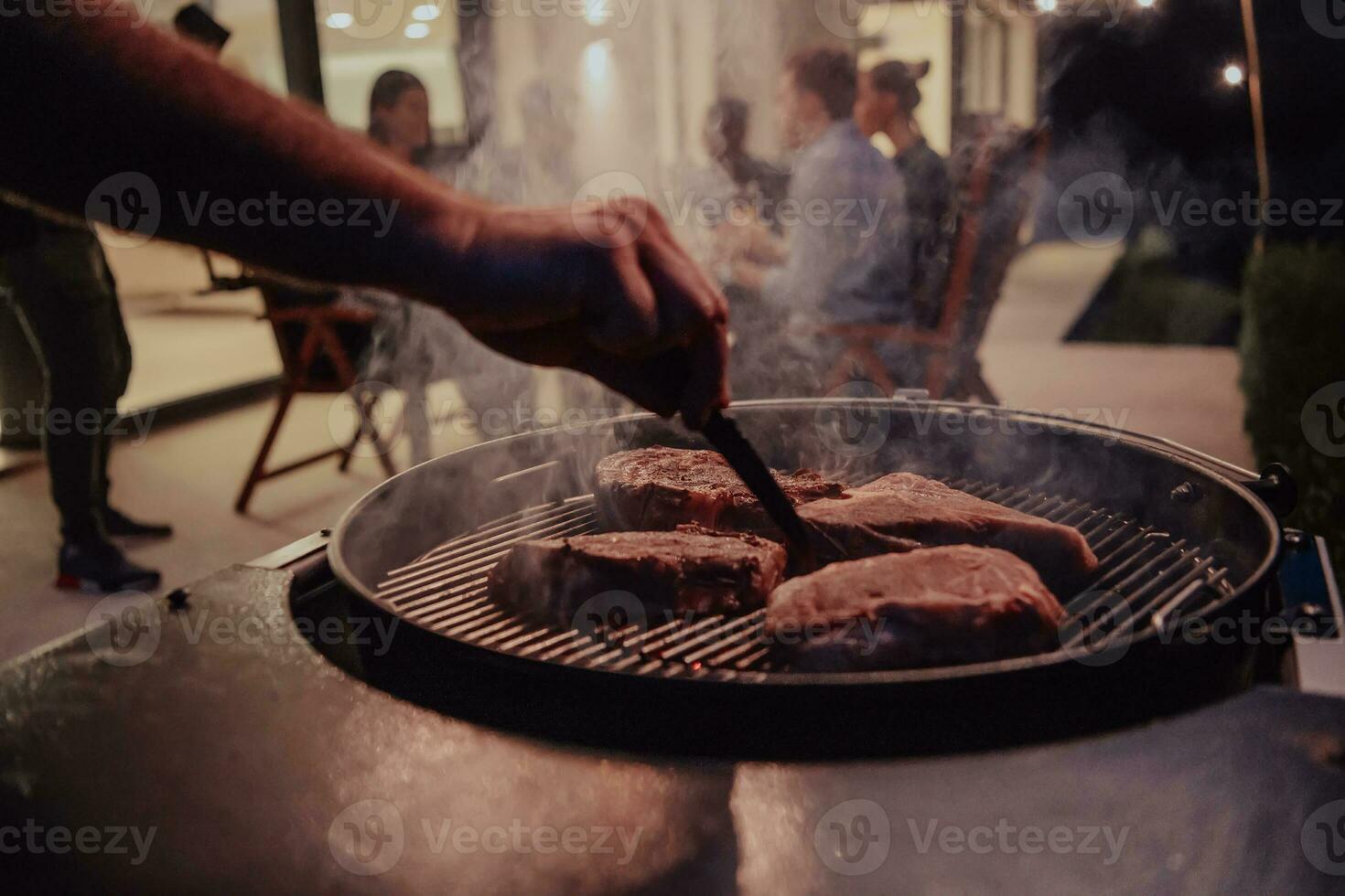 Nahansicht Foto von köstlich Fleisch Sein gegrillt. im das Hintergrund, freunde und Familie sind Sitzung und warten zum ein Mahlzeit