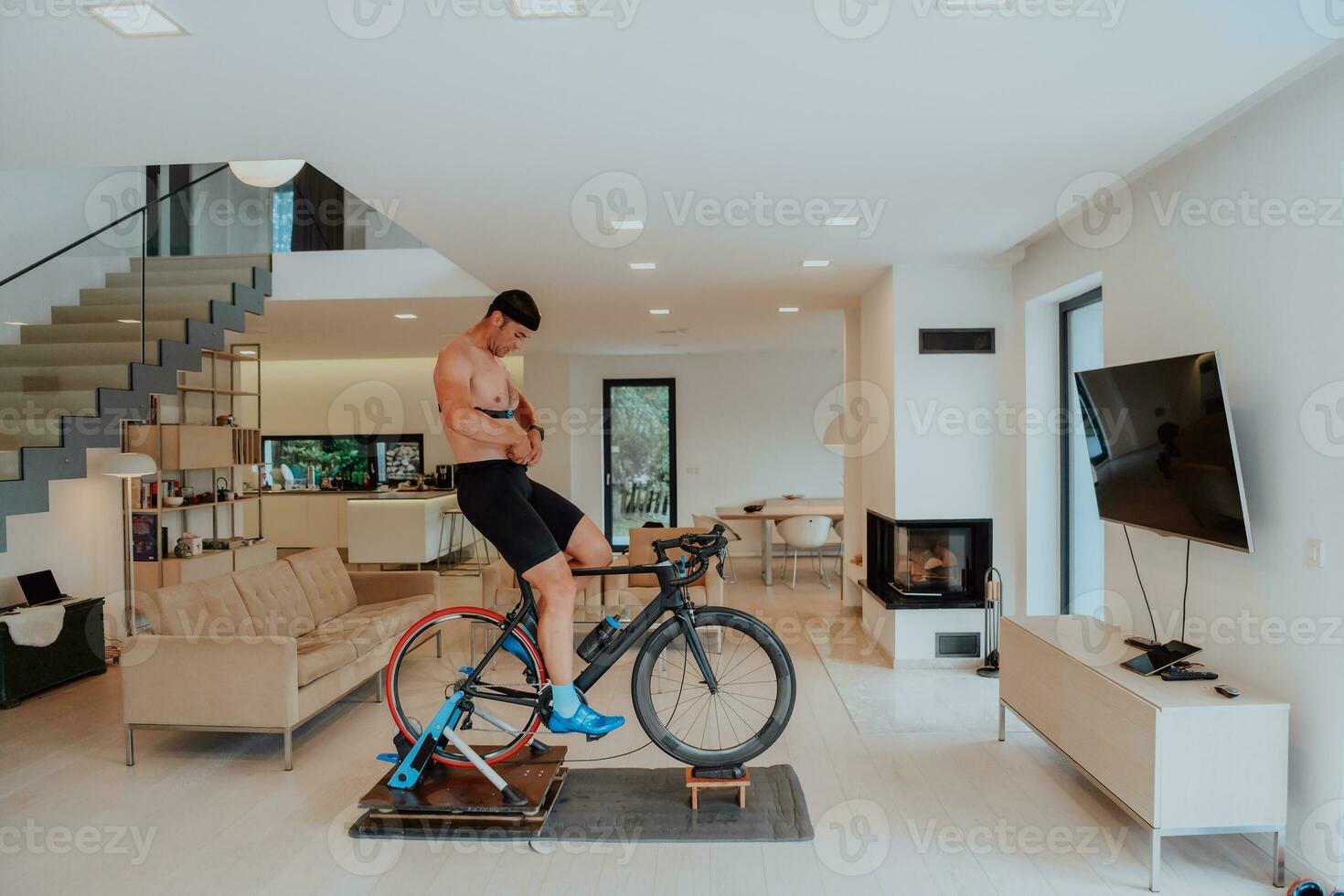 ein Mann Reiten ein Triathlon Fahrrad auf ein Maschine Simulation im ein modern Leben Zimmer. Ausbildung während Pandemie Bedingungen. foto