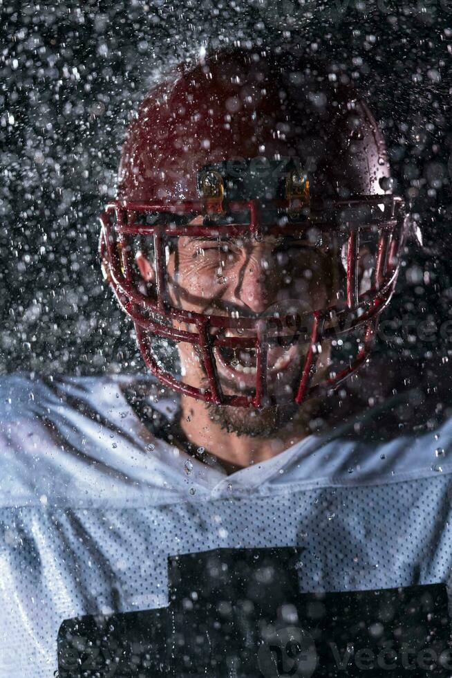 amerikanisch Fußball Feld einsam Athlet Krieger Stehen auf ein Feld hält seine Helm und bereit zu spielen. Spieler vorbereiten zu laufen, Attacke und Ergebnis Landung. regnerisch Nacht mit dramatisch Nebel, Blau Licht foto