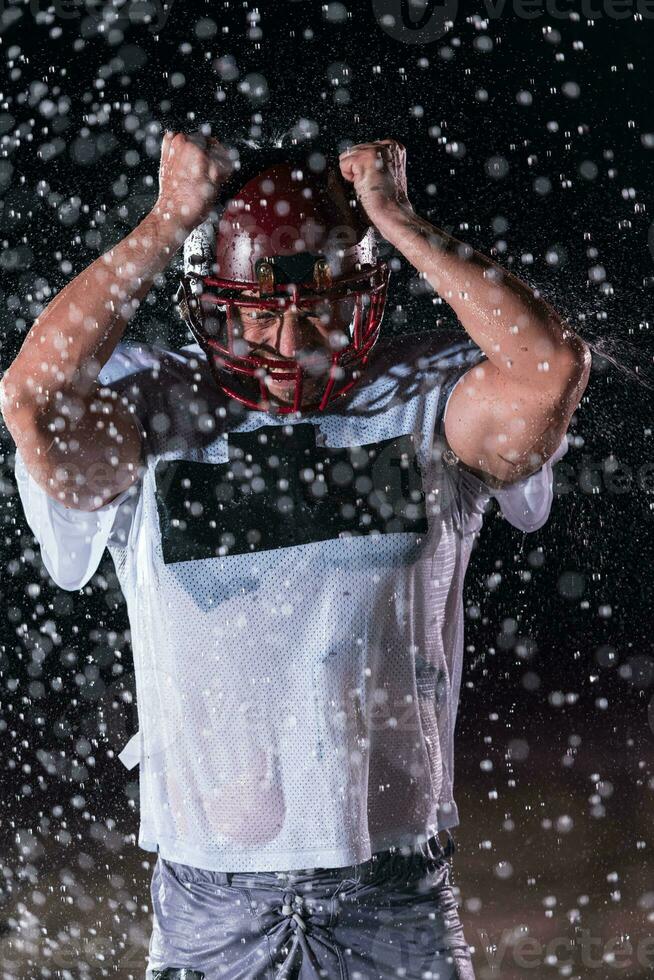 amerikanisch Fußball Feld einsam Athlet Krieger Stehen auf ein Feld hält seine Helm und bereit zu spielen. Spieler vorbereiten zu laufen, Attacke und Ergebnis Landung. regnerisch Nacht mit dramatisch Nebel, Blau Licht foto