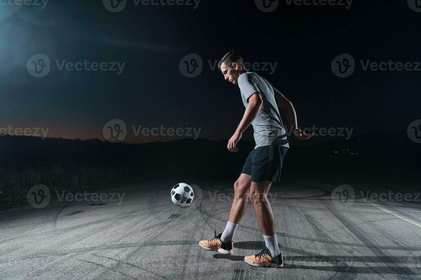 Porträt von ein jung gut aussehend Fußball Spieler Mann auf ein Straße spielen mit ein Fußball Ball. foto