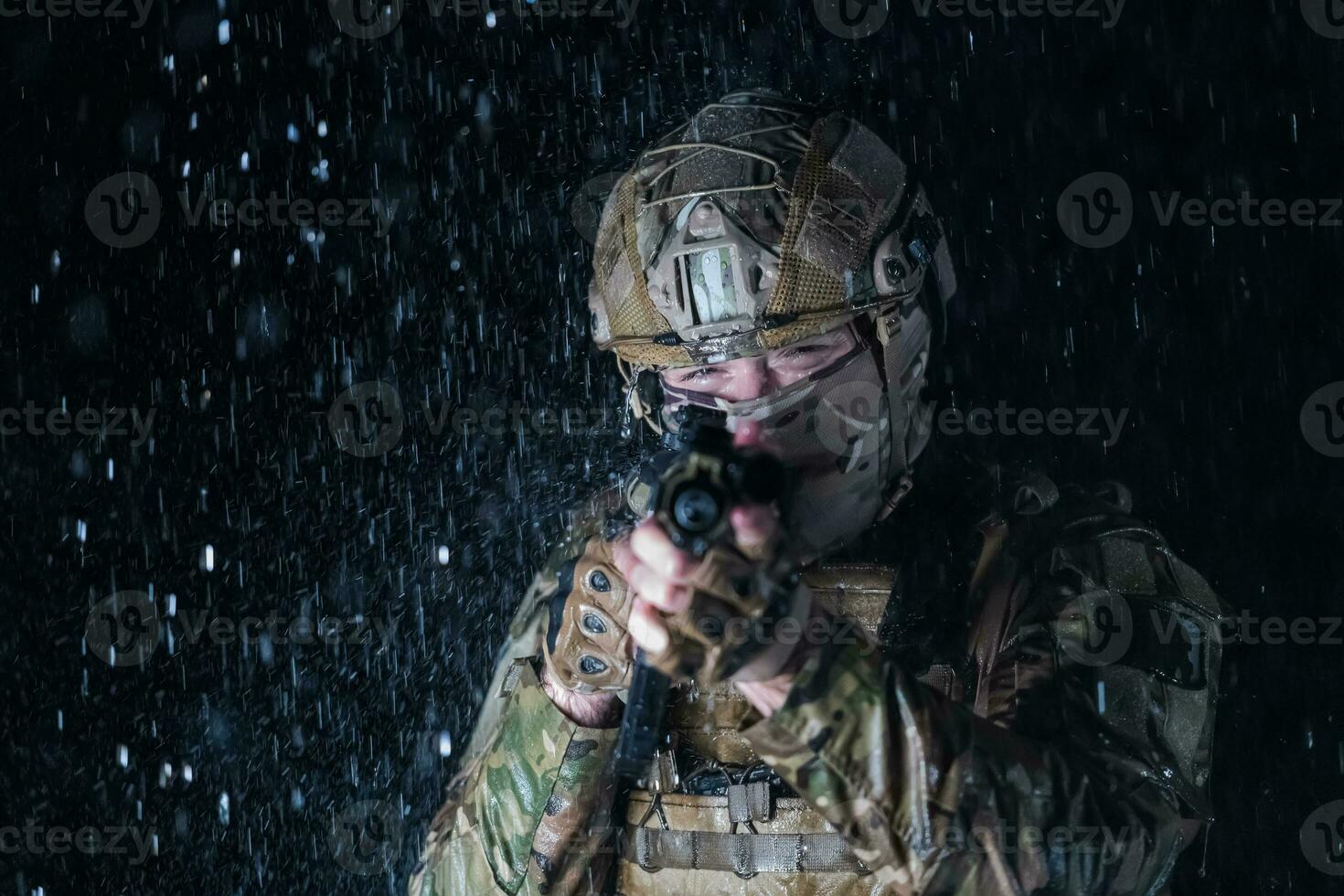 Heer Soldat im Kampf Uniformen mit ein Angriff Gewehr, Teller Träger und Kampf Helm gehen auf ein gefährlich Mission auf ein regnerisch Nacht. foto