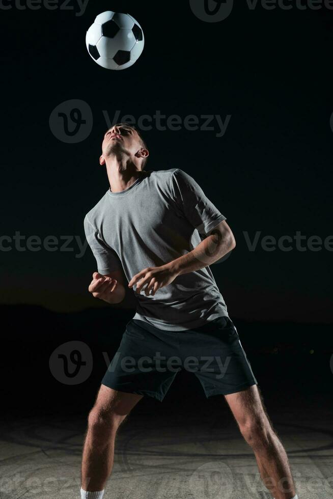 Porträt von ein jung gut aussehend Fußball Spieler Mann auf ein Straße spielen mit ein Fußball Ball. foto