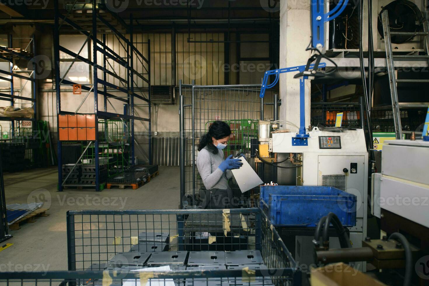 Frau, die in der Metallindustrie bei der Herstellung neuer Maschinen arbeitet, trägt während der Arbeit aufgrund der Coronavirus-Pandemie eine Gesichtsmaske foto