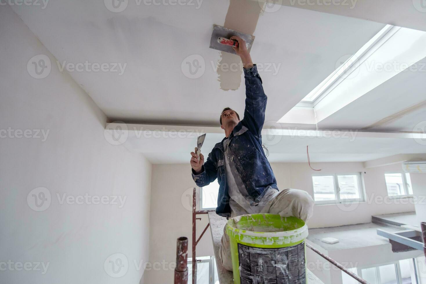 bauarbeiter, der auf gipsdecke verputzt foto