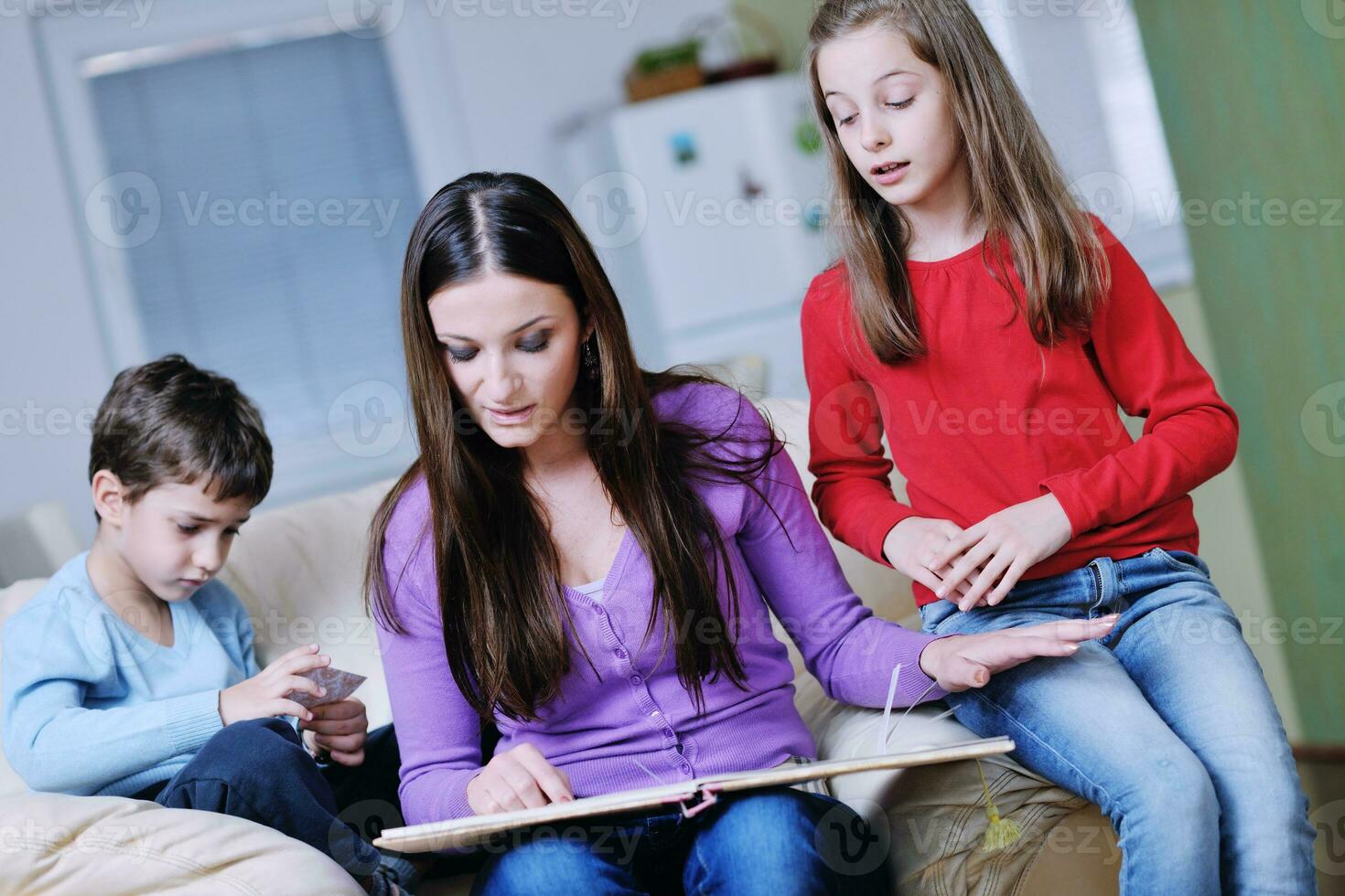 junge mutter spielt mit ihren kindern zu hause und liest buch foto