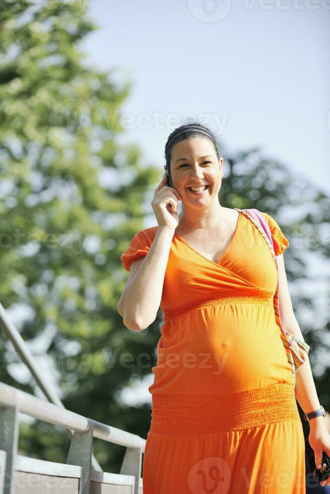 glückliche schwangere Frau, die per Handy spricht foto
