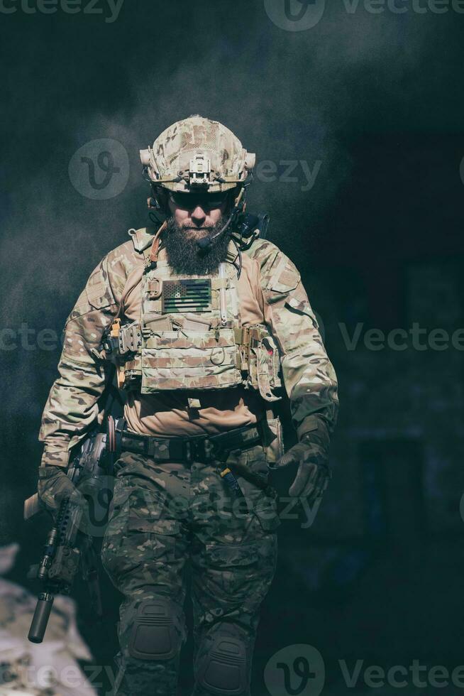 Ein bärtiger Soldat in einer Uniform der Spezialeinheit geht nach einer erfolgreichen Mission durch ein verlassenes Gebäude. Auswahl Fokus foto