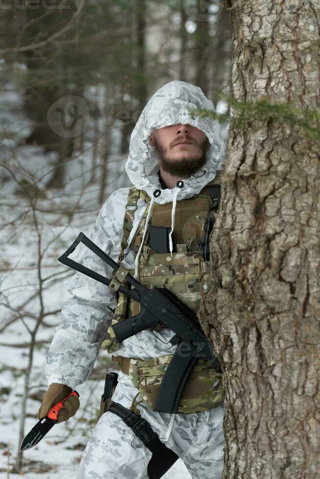 Winterkrieg in den arktischen Bergen. einsatz bei kalten bedingungen. soldat im winter getarnte uniform in der modernen kriegsarmee an einem schneetag auf dem waldschlachtfeld mit einem gewehr. selektiver Fokus foto