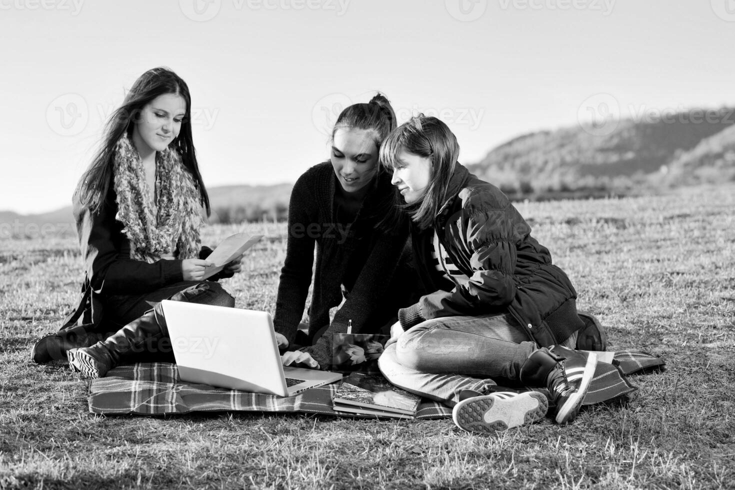 Gruppe von Teenagern, die im Freien am Laptop arbeiten foto