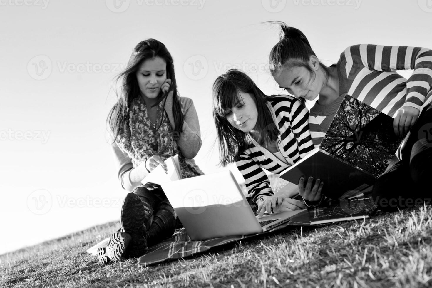 Gruppe von Teenagern, die im Freien am Laptop arbeiten foto