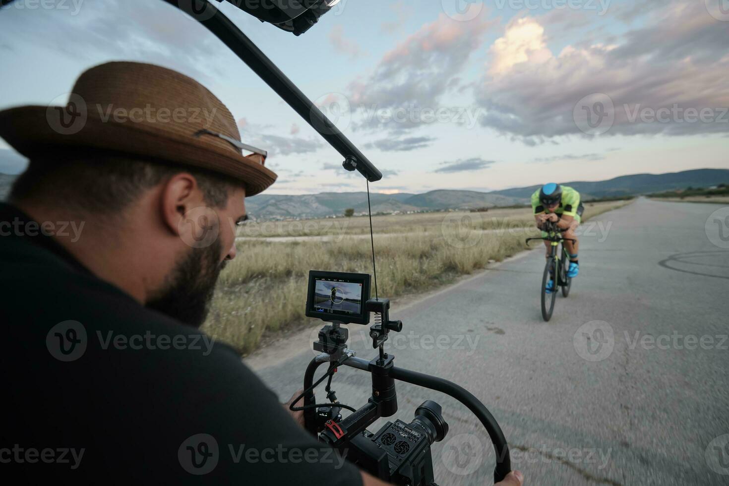 Videofilmer, der beim Fahrradfahren eine Action-Aufnahme eines Triathlon-Athleten macht foto