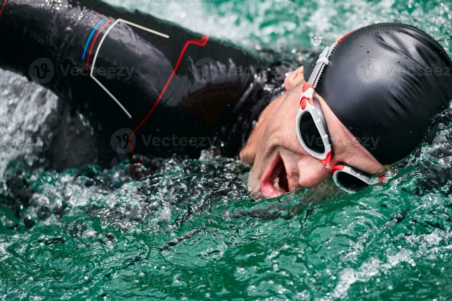 Triathlon-Athlet, der auf dem See schwimmt und einen Neoprenanzug trägt foto