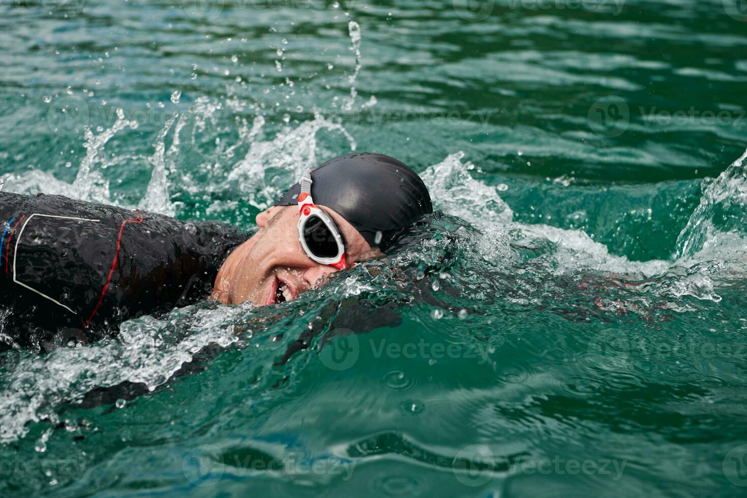 Triathlon-Athlet, der auf dem See schwimmt und einen Neoprenanzug trägt foto