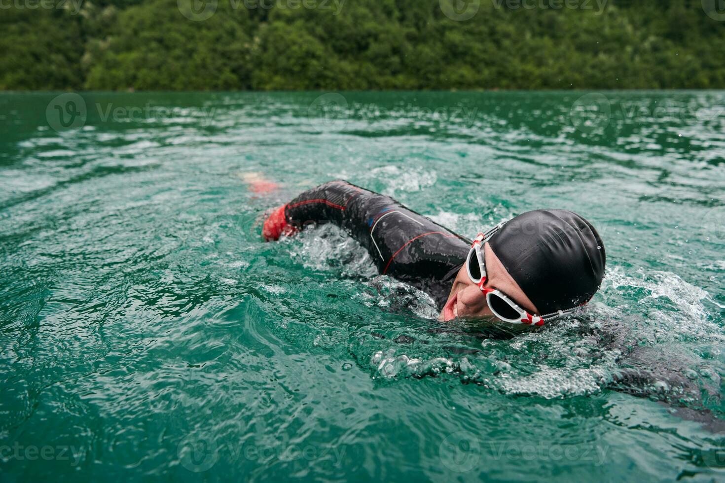 Triathlon-Athlet, der auf dem See schwimmt und einen Neoprenanzug trägt foto