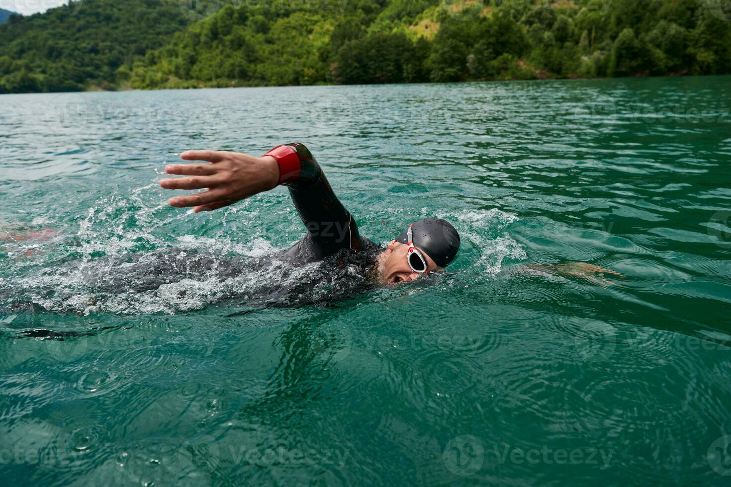 Triathlon-Athlet, der auf dem See schwimmt und einen Neoprenanzug trägt foto