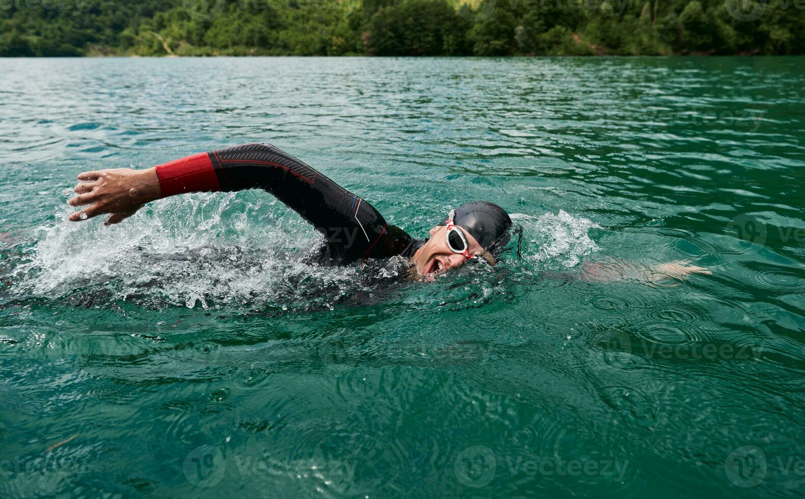 Triathlon-Athlet, der auf dem See schwimmt und einen Neoprenanzug trägt foto