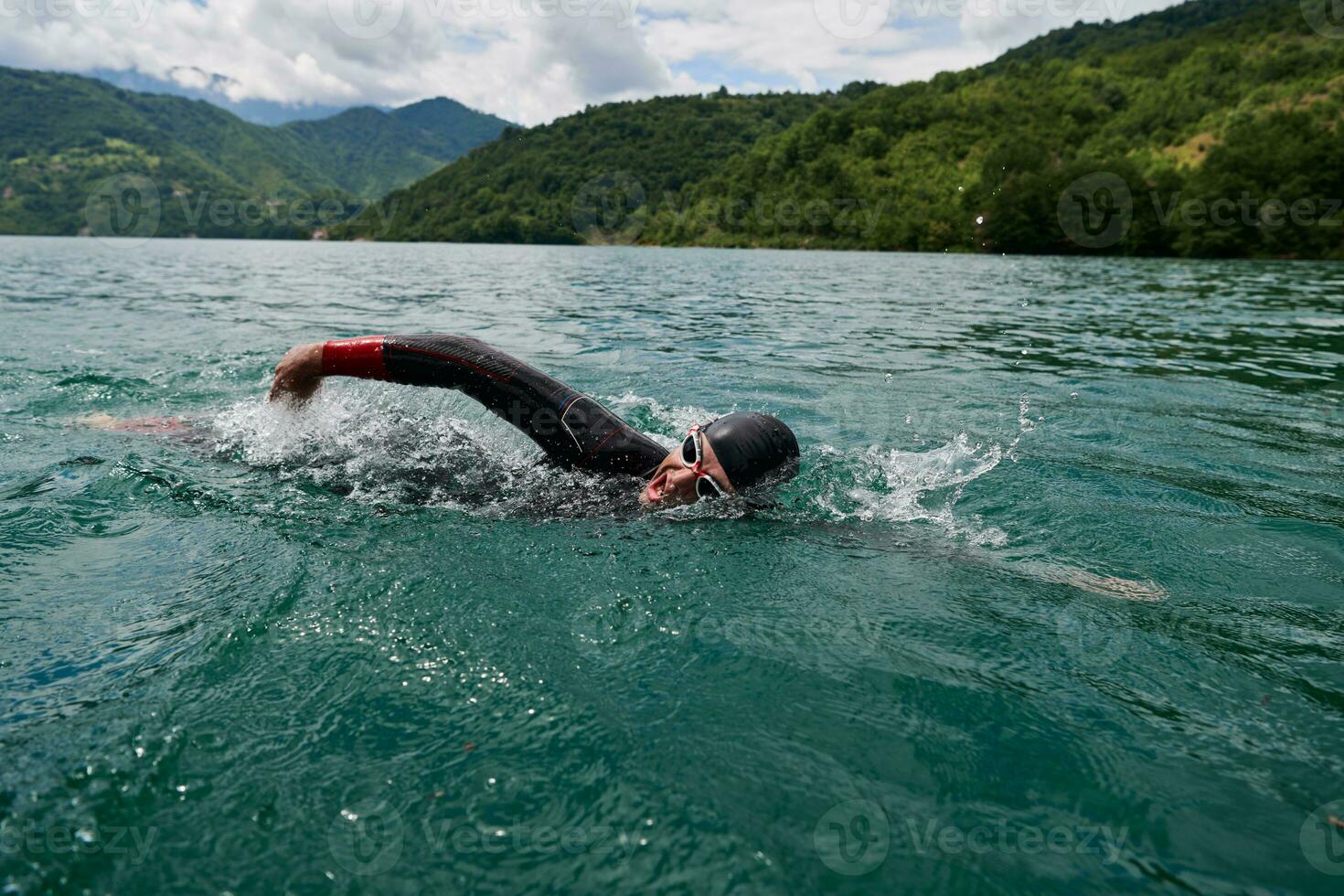 Triathlon-Athlet, der auf dem See schwimmt und einen Neoprenanzug trägt foto