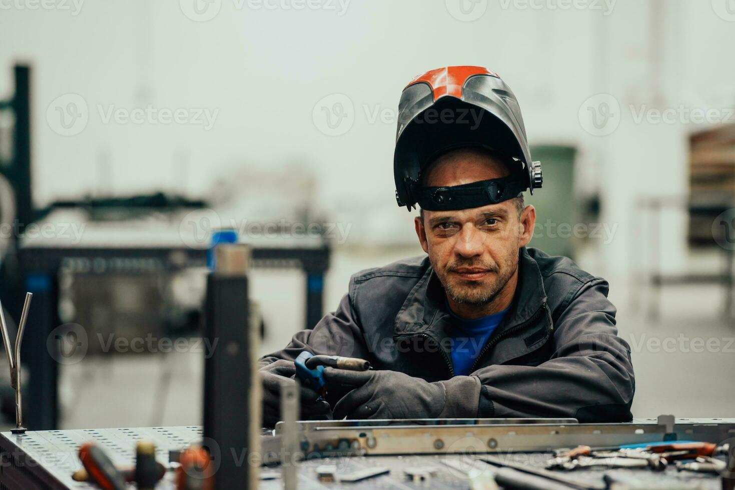 professioneller Schweißer aus der Schwerindustrie, der in der Fabrik arbeitet, einen Helm trägt und mit dem Schweißen beginnt. selektiver Fokus foto