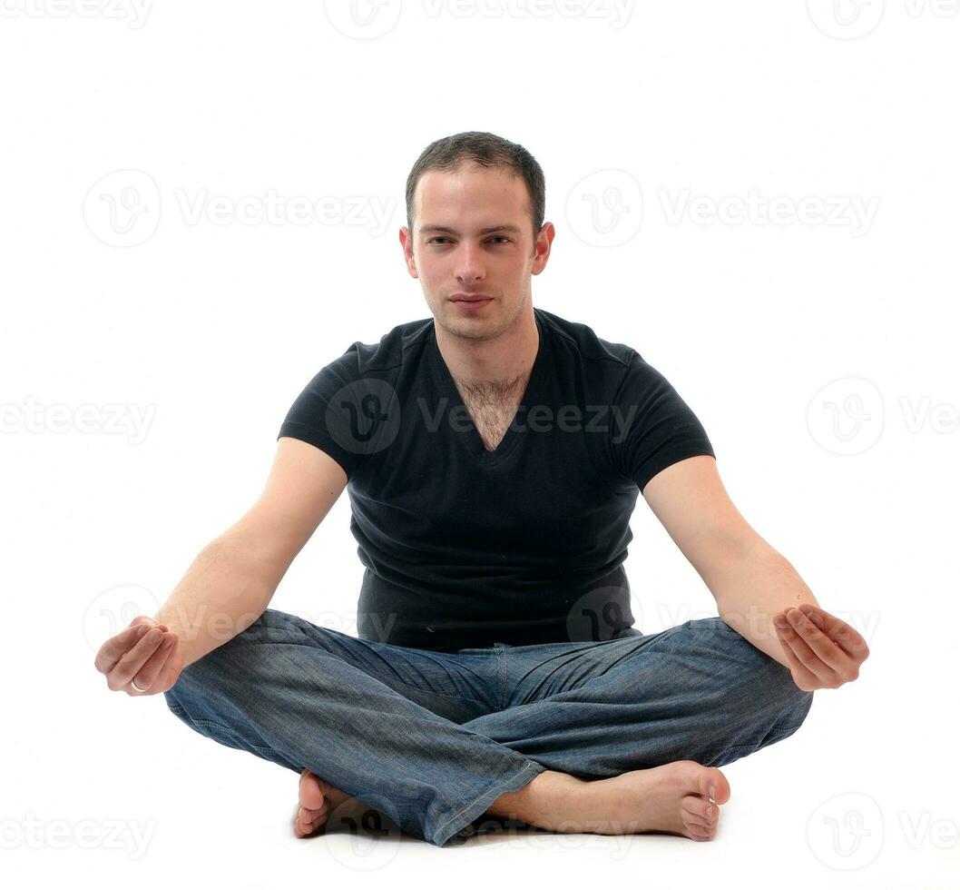 junger Mann im Lotussitz, der Yoga ausübt foto