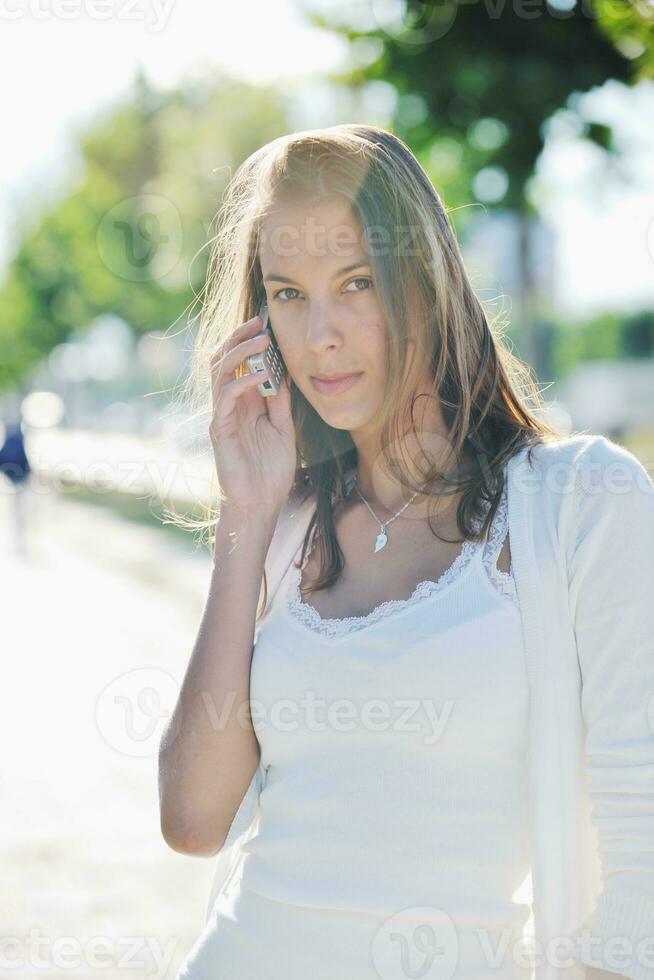 Junge Frau spricht per Handy auf der Straße foto