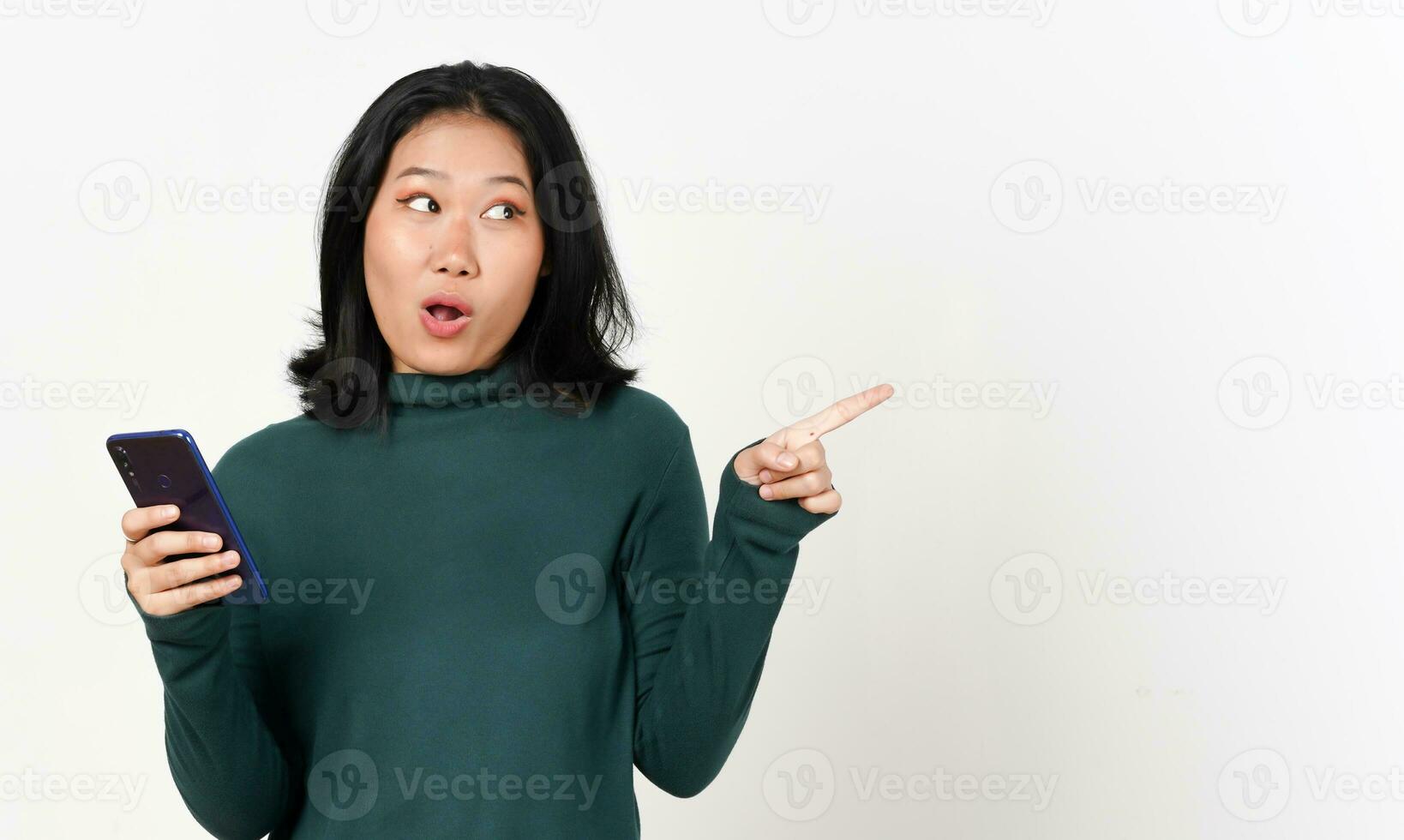 halten Smartphone glücklich Gesicht während zeigen Seite Mauer Kopieren Raum von schön asiatisch Frau isoliert auf Weiß Hintergrund foto