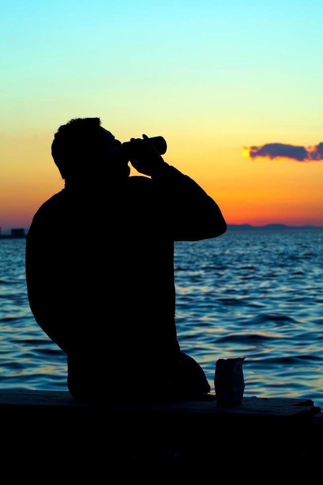 Menschensilhouette und das Meer im Sonnenuntergang foto