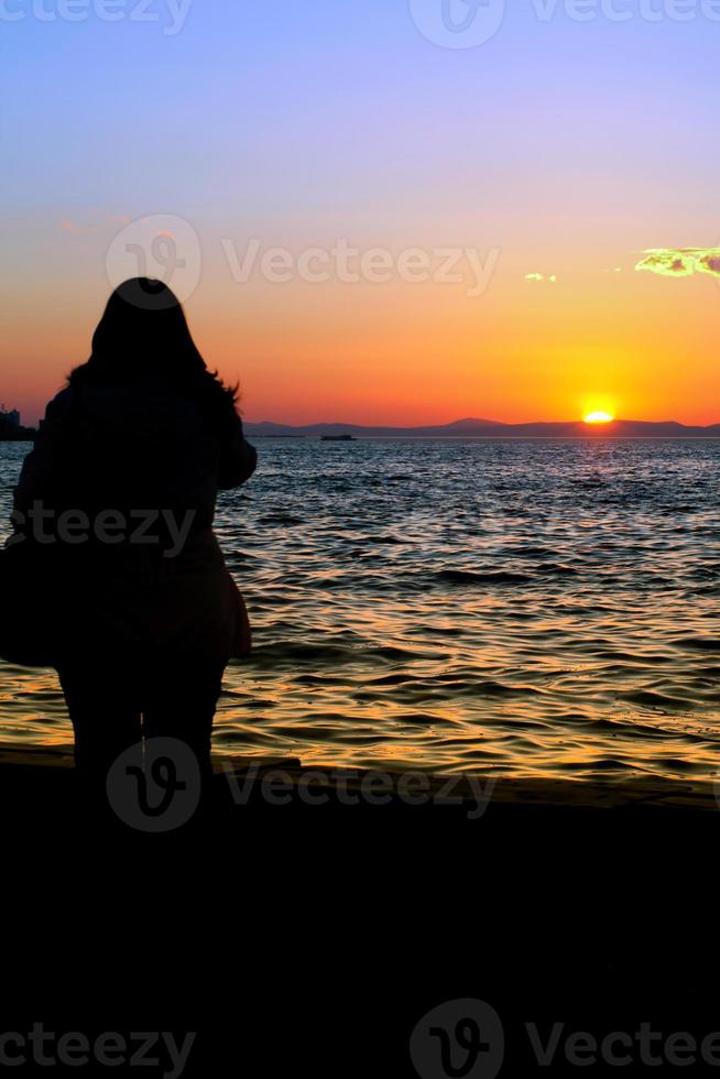 Menschensilhouette und das Meer im Sonnenuntergang foto