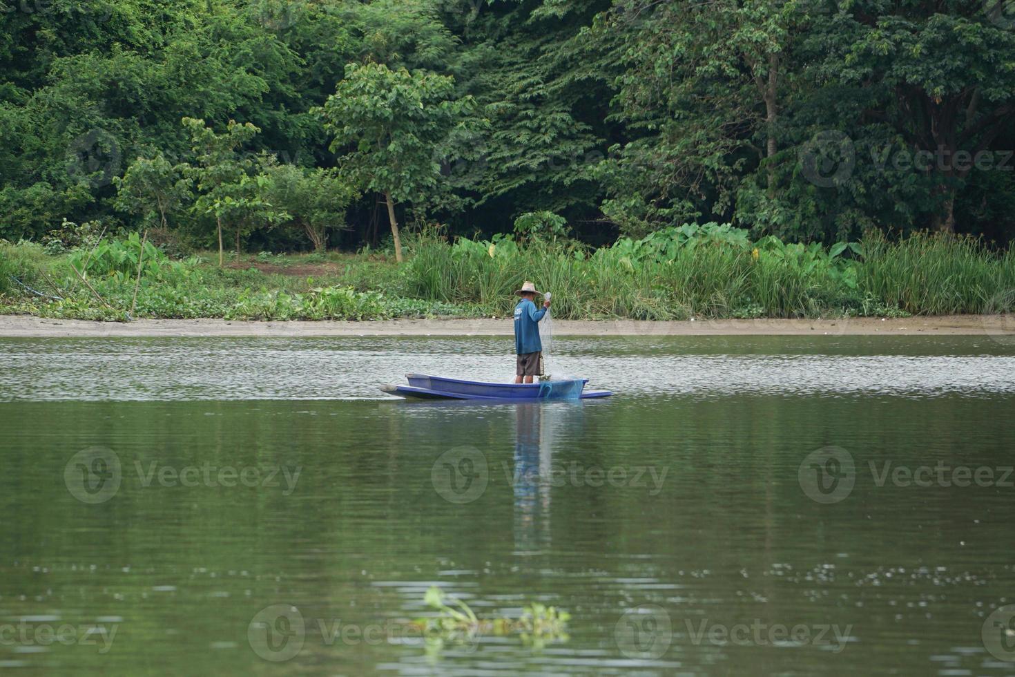 einsamer Mann steht auf dem Boot und sammelt den Fisch aus dem Netz foto