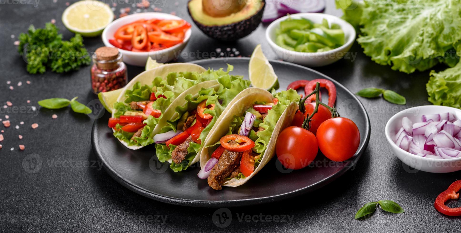 mexikanische Tacos mit Rindfleisch, Tomaten, Avocado, Zwiebeln und Salsasauce foto