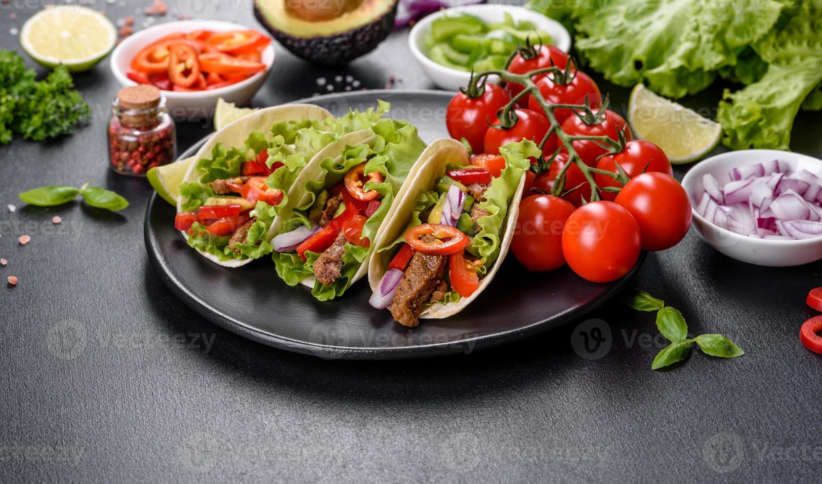 mexikanische Tacos mit Rindfleisch, Tomaten, Avocado, Zwiebeln und Salsasauce foto