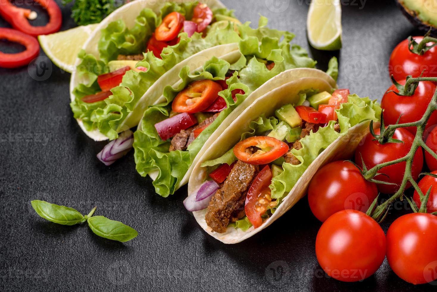 mexikanische Tacos mit Rindfleisch, Tomaten, Avocado, Zwiebeln und Salsasauce foto