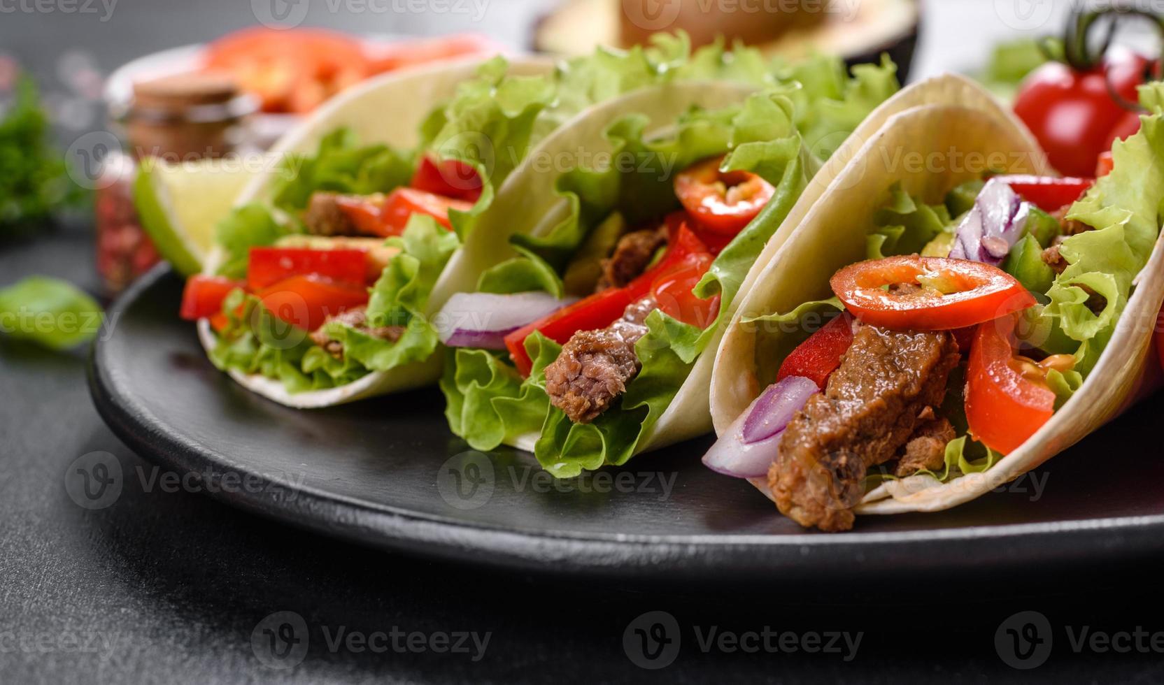 mexikanische Tacos mit Rindfleisch, Tomaten, Avocado, Zwiebeln und Salsasauce foto