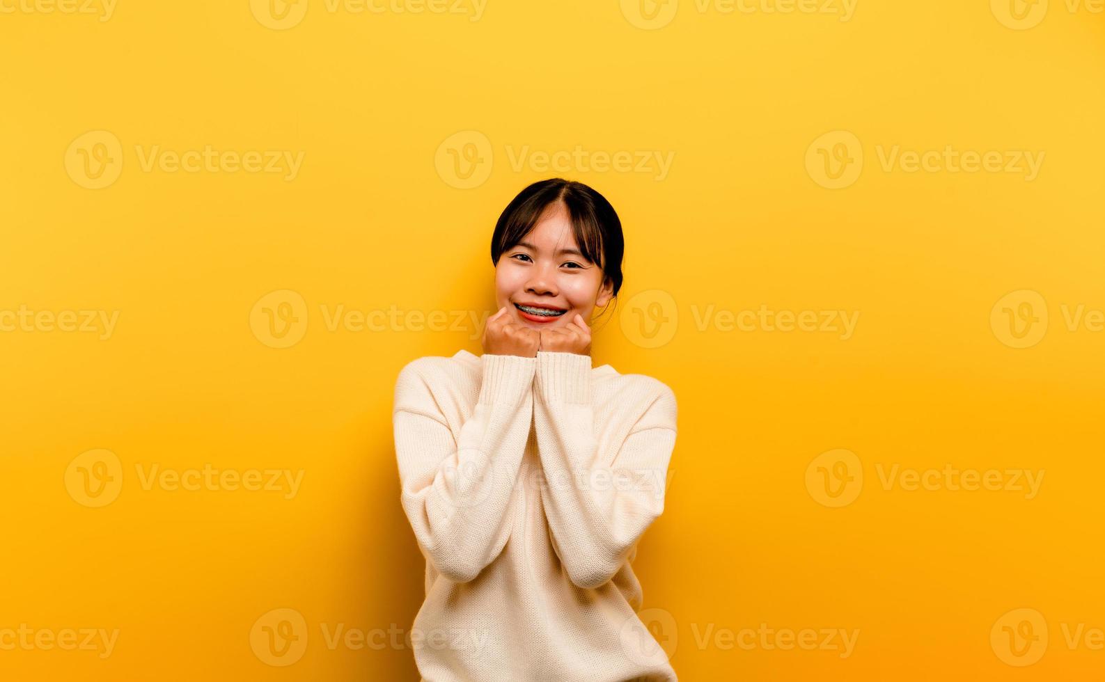 asiatisches mädchen, das ein weißes lässiges kleid auf einem gelben trägt foto