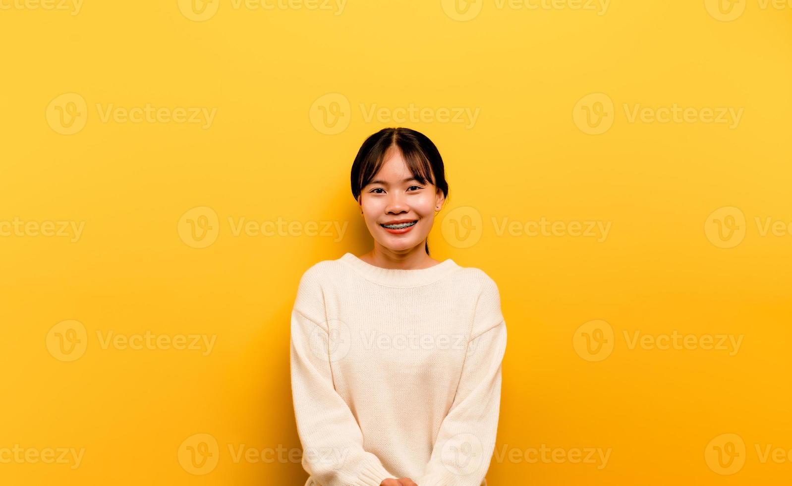 asiatisches mädchen, das ein weißes lässiges kleid auf einem gelben trägt foto