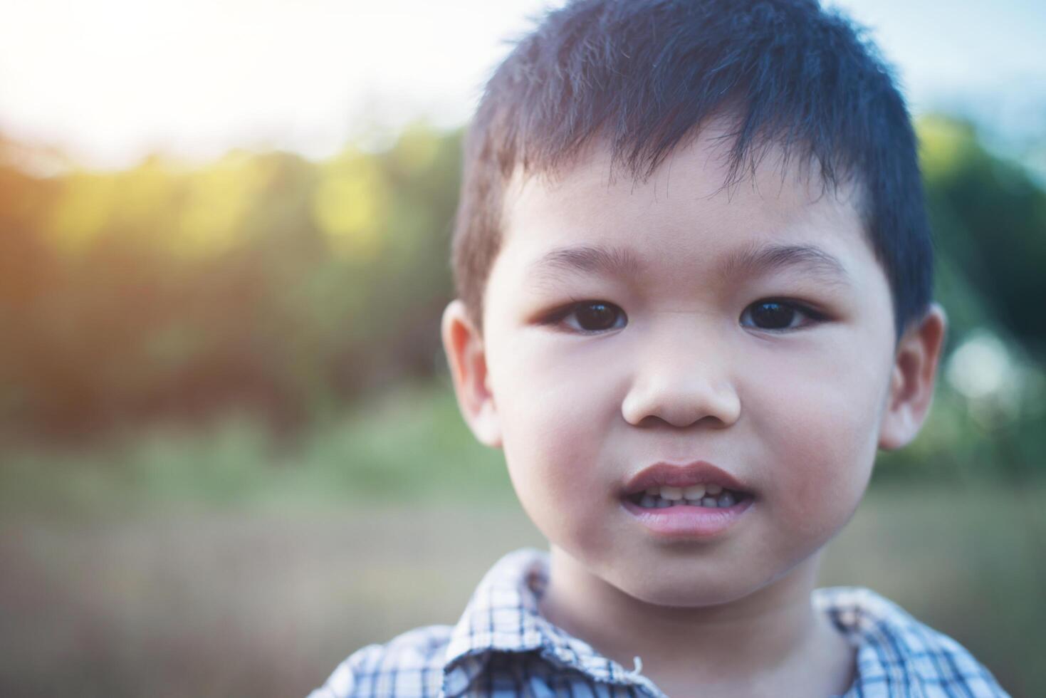 Nahaufnahme eines süßen asiatischen Jungen, der im Freien spielt und lächelt. foto