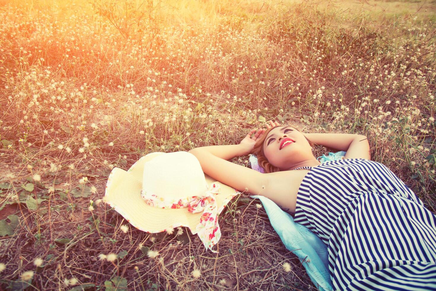 junge sexy Frau im Gras liegend nähert sich ihrem Hut Blick in den Himmel. foto