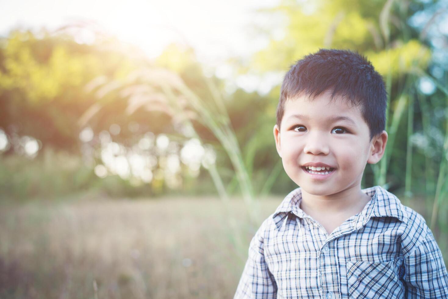 Nahaufnahme eines süßen asiatischen Jungen, der im Freien spielt und lächelt. foto