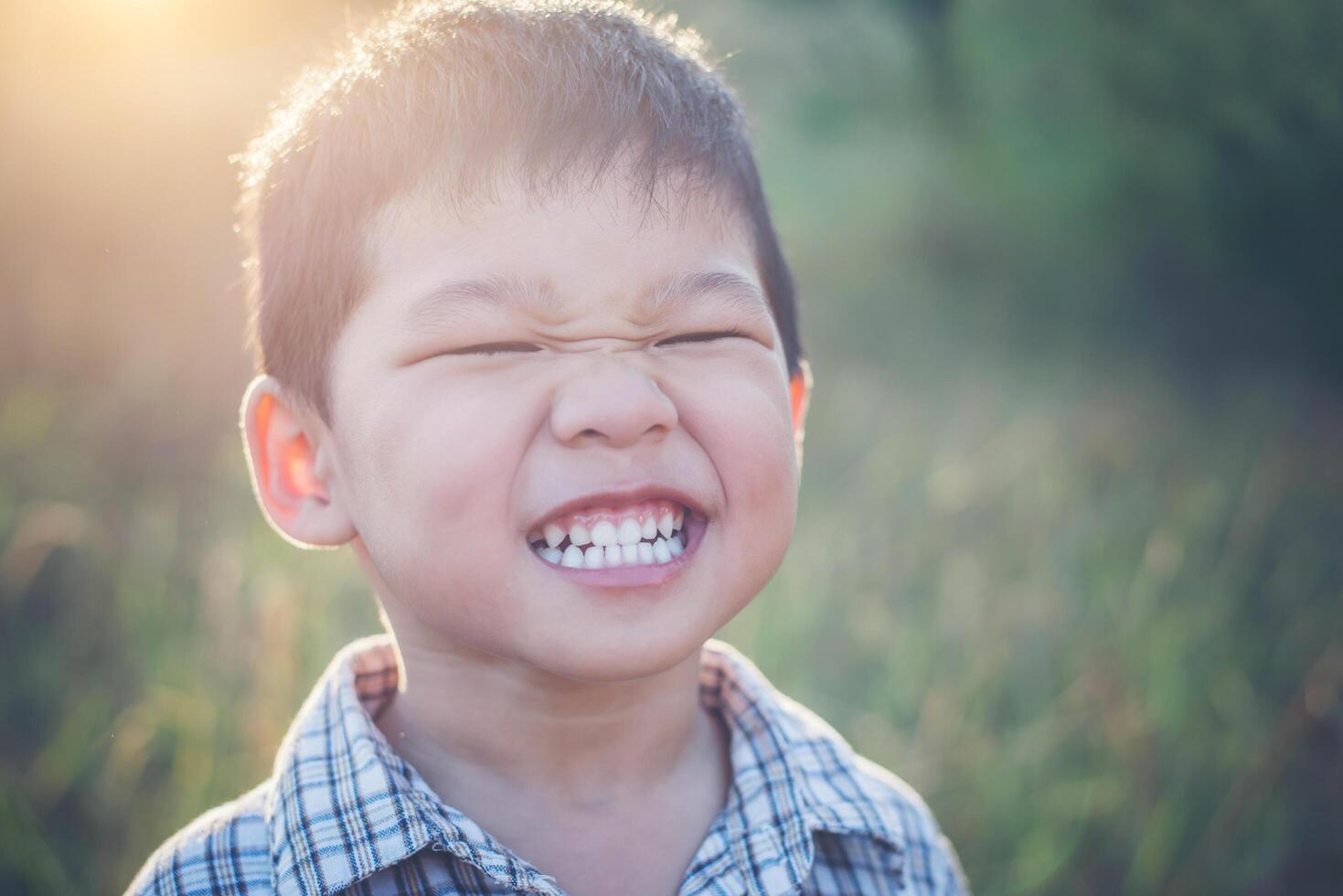 Nahaufnahme eines süßen asiatischen Jungen, der im Freien spielt und lächelt. foto